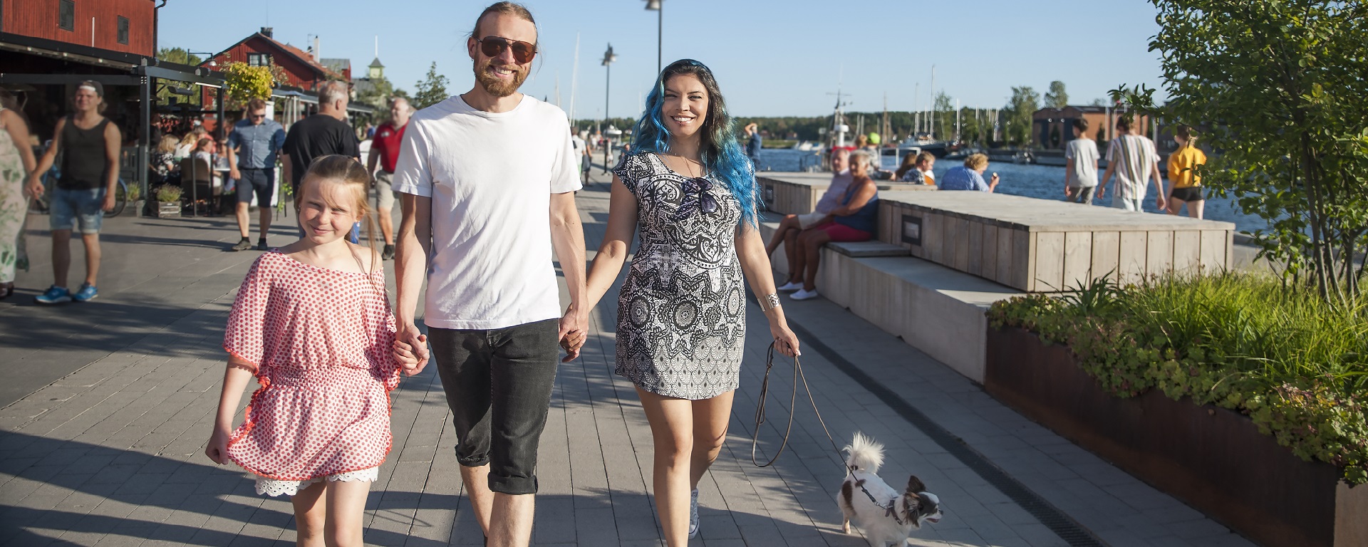 En familj promenerar med sin hund i Nyköpings folkfulla hamn.